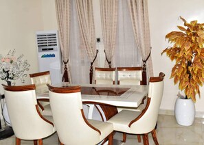 A dining area with a table and chairs, an air conditioning unit, and a potted plant. - Impeccable 4 Bed House In Lagos Nigeria (Lekki)