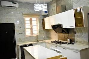 A modern kitchen with a built-in dishwasher, a gas stove, and a window with blinds. - Impeccable 4 Bed House In Lagos Nigeria (Lekki)