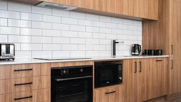 A kitchen with wooden cabinets, a white tiled backsplash, a toaster, a coffee maker, and an oven.