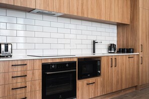 Eine Küche mit Holzschränken, einer weißen Fliesenspiegel, einem Toaster, einer Kaffeemaschine und einem Backofen.