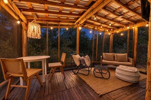 Eine Terrasse aus Holz mit Tisch, Stühlen, einem Schaukelstuhl und einer Couch.