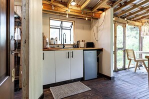 A kitchen with white cabinets, a built-in dishwasher, a window, and a wooden ceiling. - Pine Lodge Cabin: Open-Air Living in the Pines (Paige)