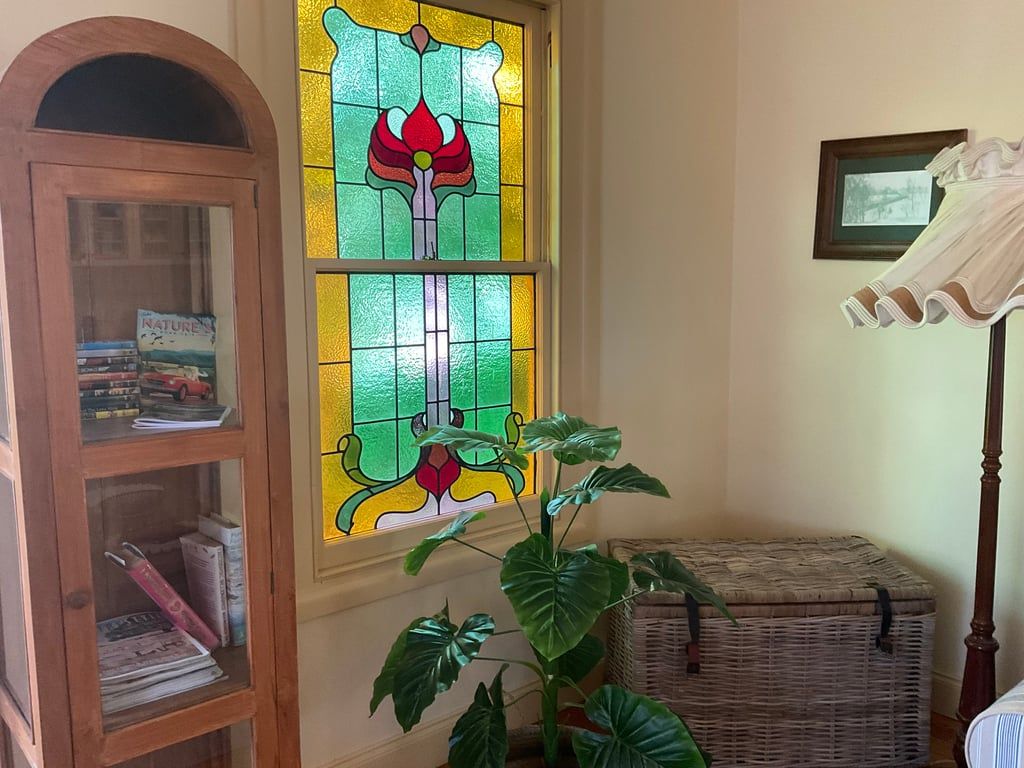 A room with a wooden cabinet, a wicker chest, and a large green plant.