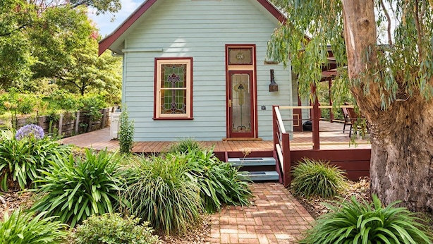 A light green house with a red roof, a front door, and a small porch with steps.