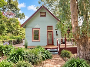A light green house with a red roof, a front door, and a small porch with steps.