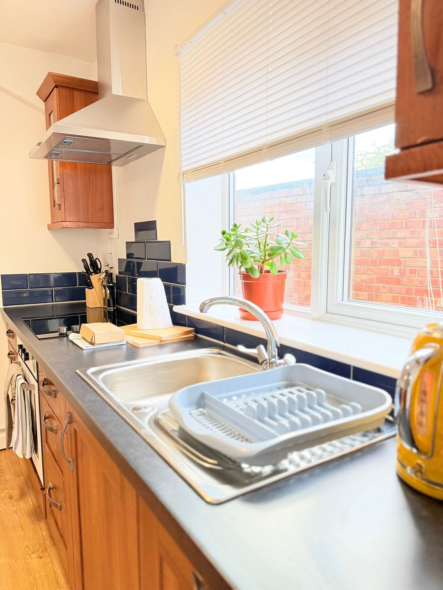 A modern kitchen with a built-in oven, a stainless steel sink, and a window with a view of a brick wall.