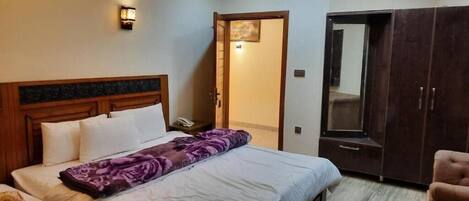A bedroom with a bed, a wardrobe, and a door leading to another room.