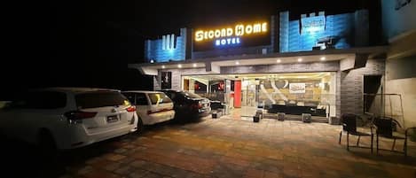 A hotel with a sign reading 'Second Home Hotel' and a parking area with several cars.