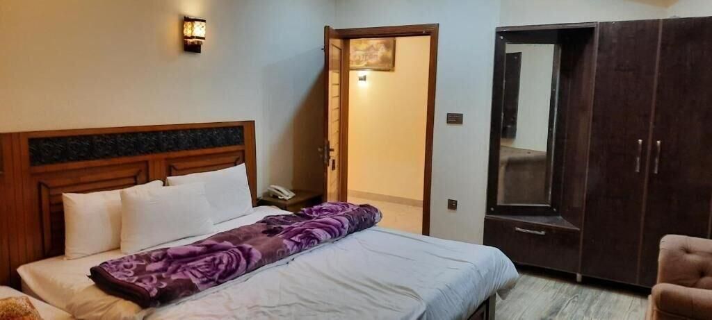 A bedroom with a bed, a wardrobe, and a door leading to another room.