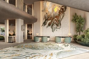 A lobby with a large abstract mural, a central seating area with a patterned rug, and a reception desk.