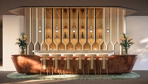 A bar area with a marble countertop, wicker chairs, and a patterned wall with bottles.
