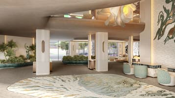 A spacious lobby with a large decorative rug, potted plants, and a seating area with a sofa and chairs.