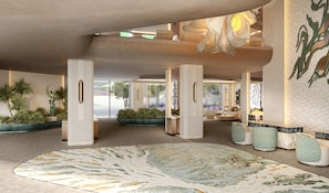 Un hall espacioso con un gran tapiz decorativo, plantas en macetas y una zona de estar con un sofá y sillones.