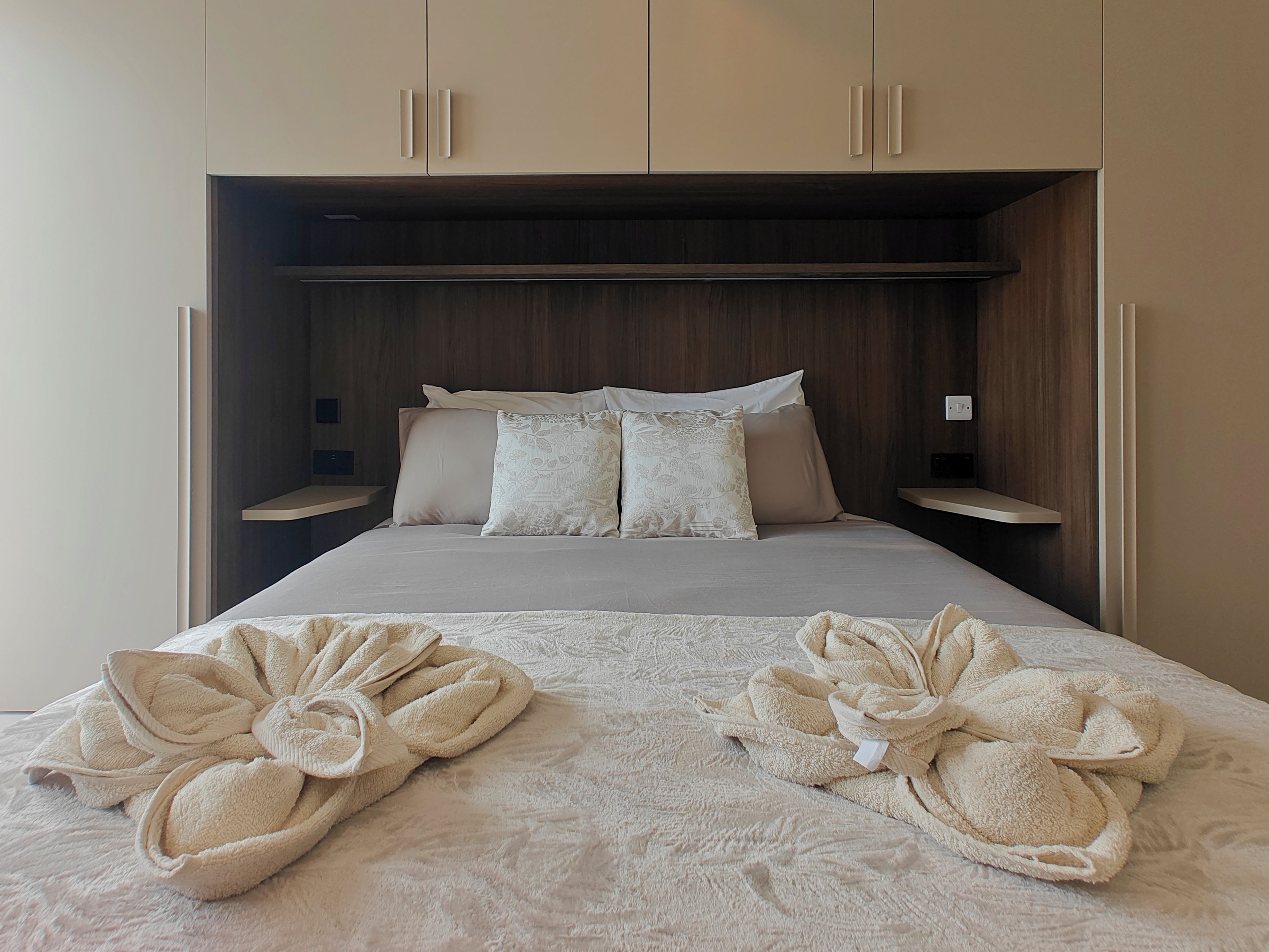 A hotel room with a bed, two bedside tables, and a wardrobe.