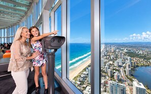 A high-rise building with a panoramic view of a coastal cityscape, including a beach and urban buildings. - City Dreams at Avani | Chic High-Rise Stay (Broadbeach)