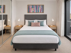 A modern bedroom with a large bed, two bedside tables, a headboard, and a colorful abstract painting above the bed. - City Dreams at Avani | Chic High-Rise Stay (Broadbeach)