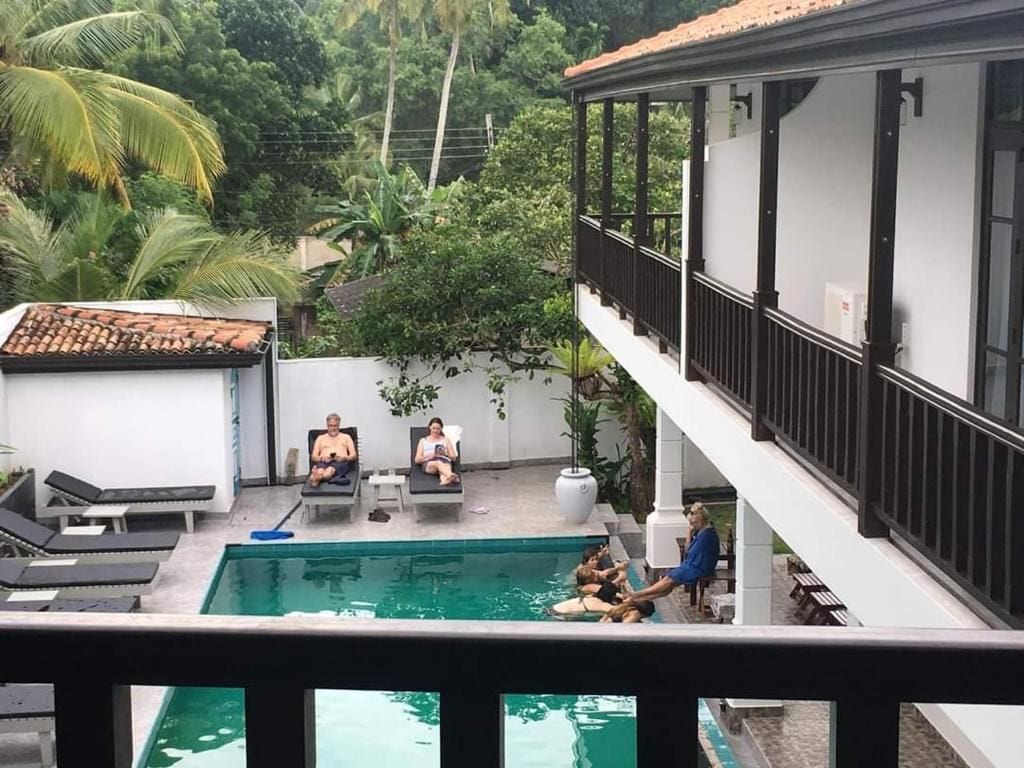 Piscina con sillas de descanso y un área techada con barandilla.
