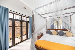 Un dormitorio con cama, cortinas y vistas a través de un ventanal.