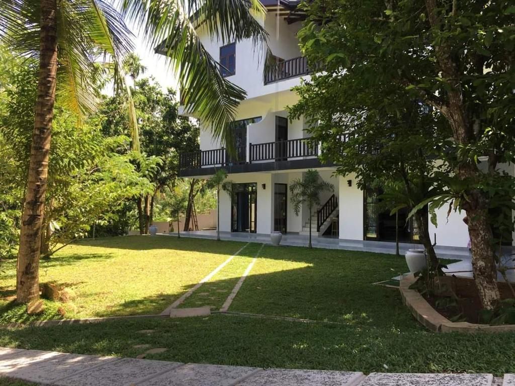 Un edificio de dos pisos con un balcón y un césped bien cuidado.