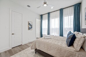 A bedroom with a bed, a ceiling fan, and a window with curtains. - Modern 2BR/2.5BA Townhome | 2-Car Garage (Dallas)