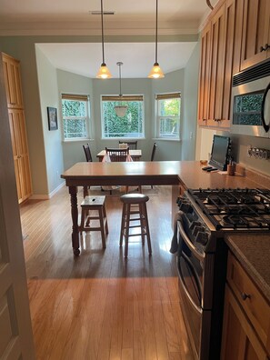 A kitchen with a central island, wooden cabinets, a gas stove, and pendant lighting.