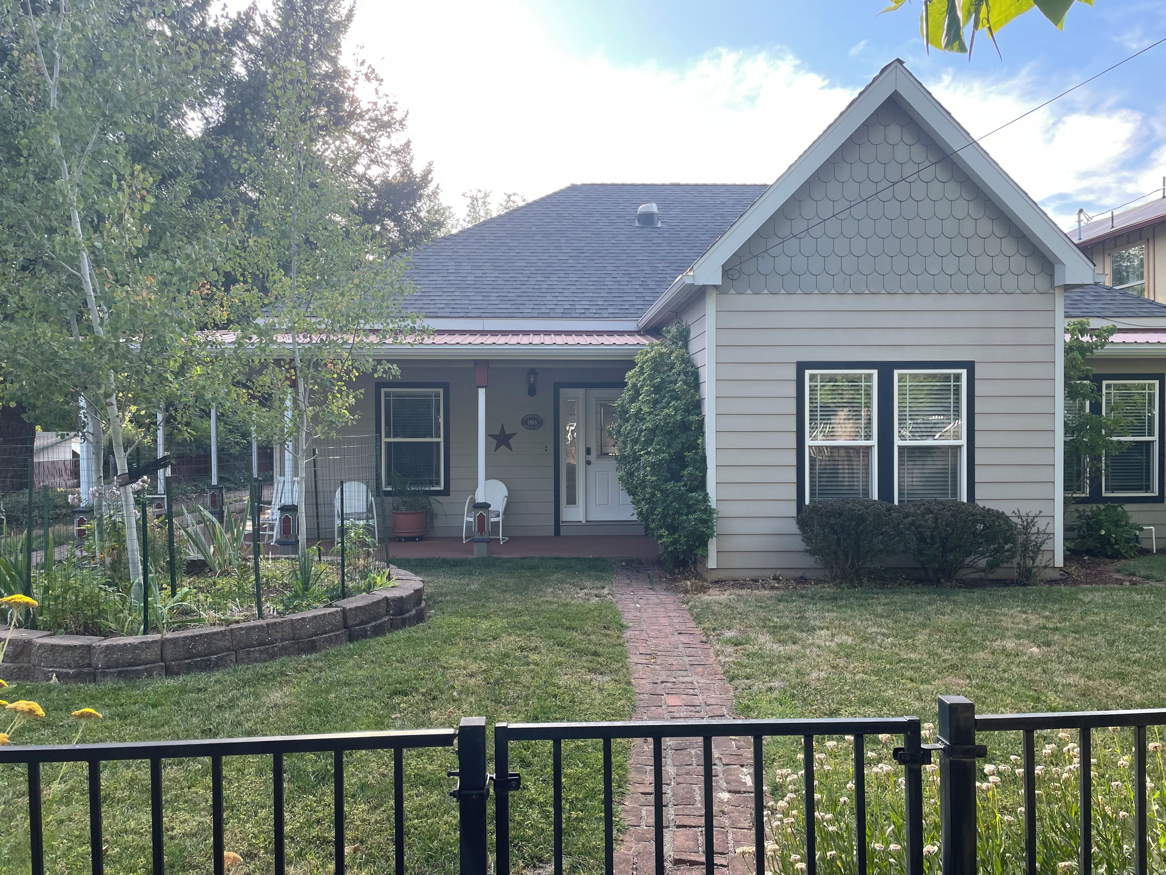A residential house with a front porch, a small garden, and a brick pathway leading to the entrance.