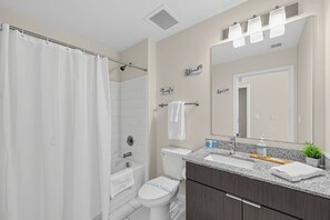 Een moderne badkamer met douche, toilet en wastafel.