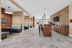 Eine moderne Hotelhalle mit einer Rezeption, einer Sitzecke und einem großen Fernsehbildschirm.