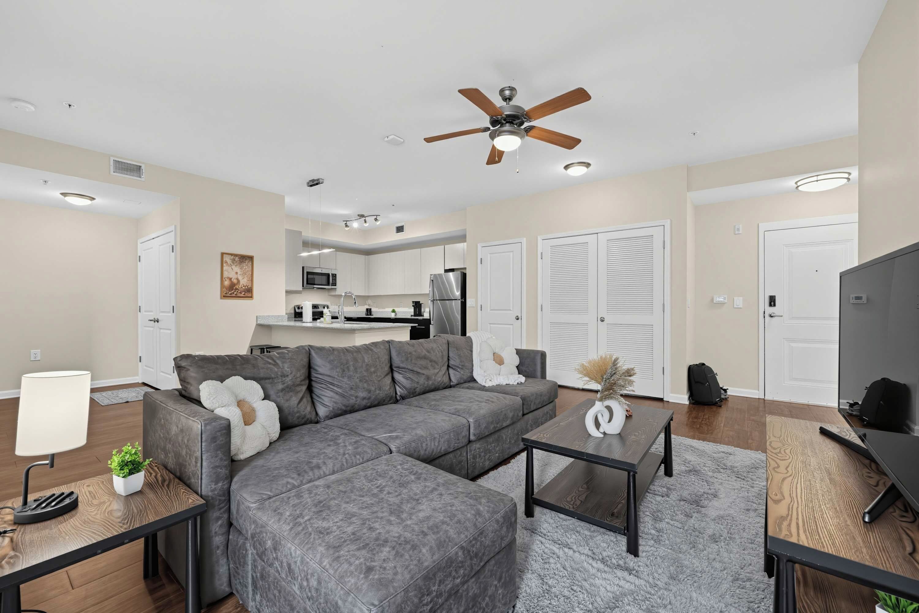 A modern living room with a sectional sofa, a coffee table, a TV, and a ceiling fan.