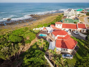 Zona residencial costera con casas, una piscina y vistas al océano.