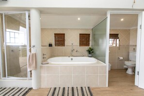 Un baño moderno con una bañera independiente, una cabina de ducha con mampara de vidrio y un inodoro.
