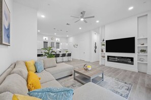 A modern living room with a sofa, coffee table, and a flat-screen TV. - Stylish 2BR/2.5BA | Garage | Near Downtown (Dallas)