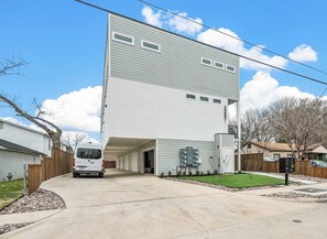 Ein modernes, zweistöckiges Gebäude mit einer Garageneinfahrt, einem Van vor der Fassade und blauem Himmel.