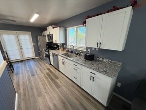 A modern kitchen with white cabinets, a granite countertop, and a stainless steel refrigerator. - High Desert Haven - Explore and unwind! —DOG FRIENDLY— (Farmington)