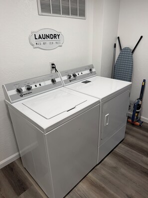 A laundry area with a Speed Queen washer and dryer, a laundry sign on the wall, and ironing boards. - High Desert Haven - Explore and unwind! —DOG FRIENDLY— (Farmington)