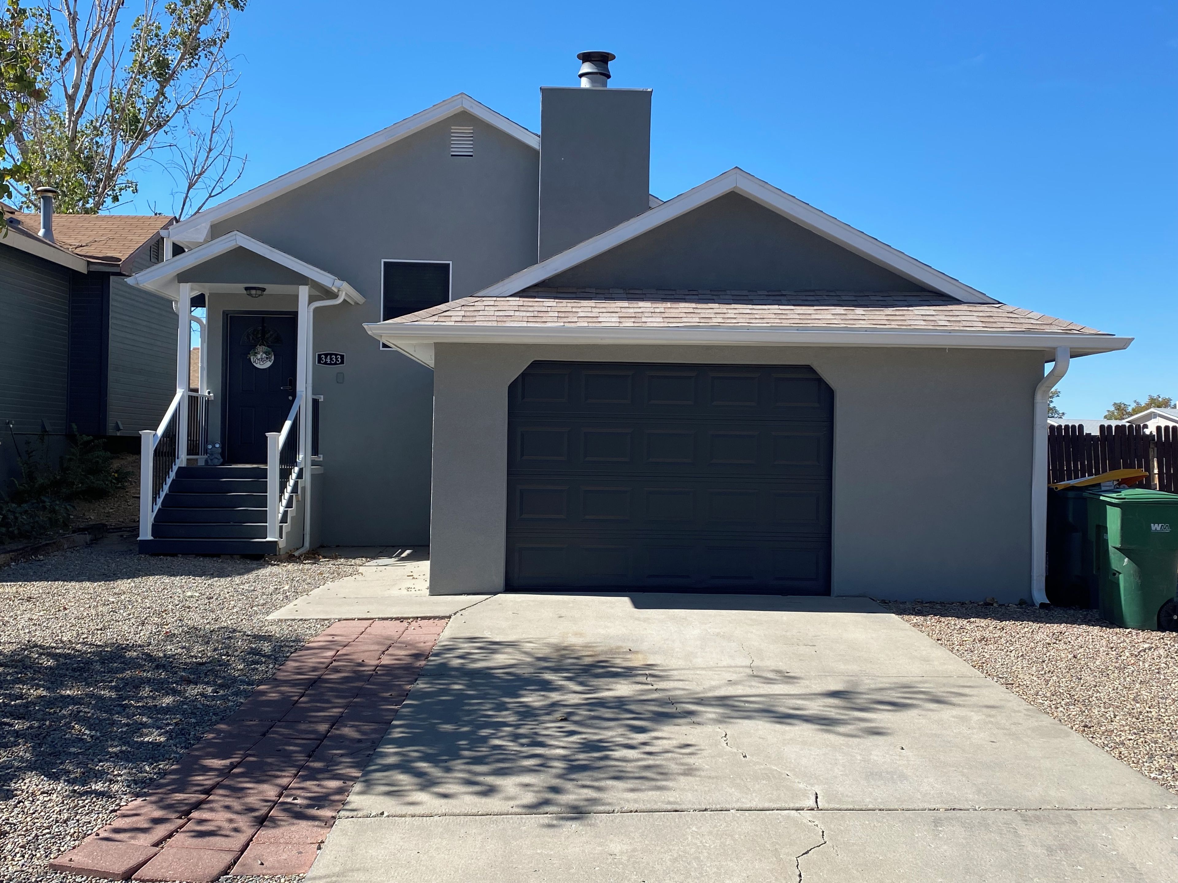 A residential house with a garage, a front door, and a staircase leading to the entrance.