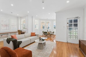 A modern living room with a sofa, coffee table, and dining area. - Harbourside Retreat | 1 min Walk from Ferry to CBD (Cremorne Point)