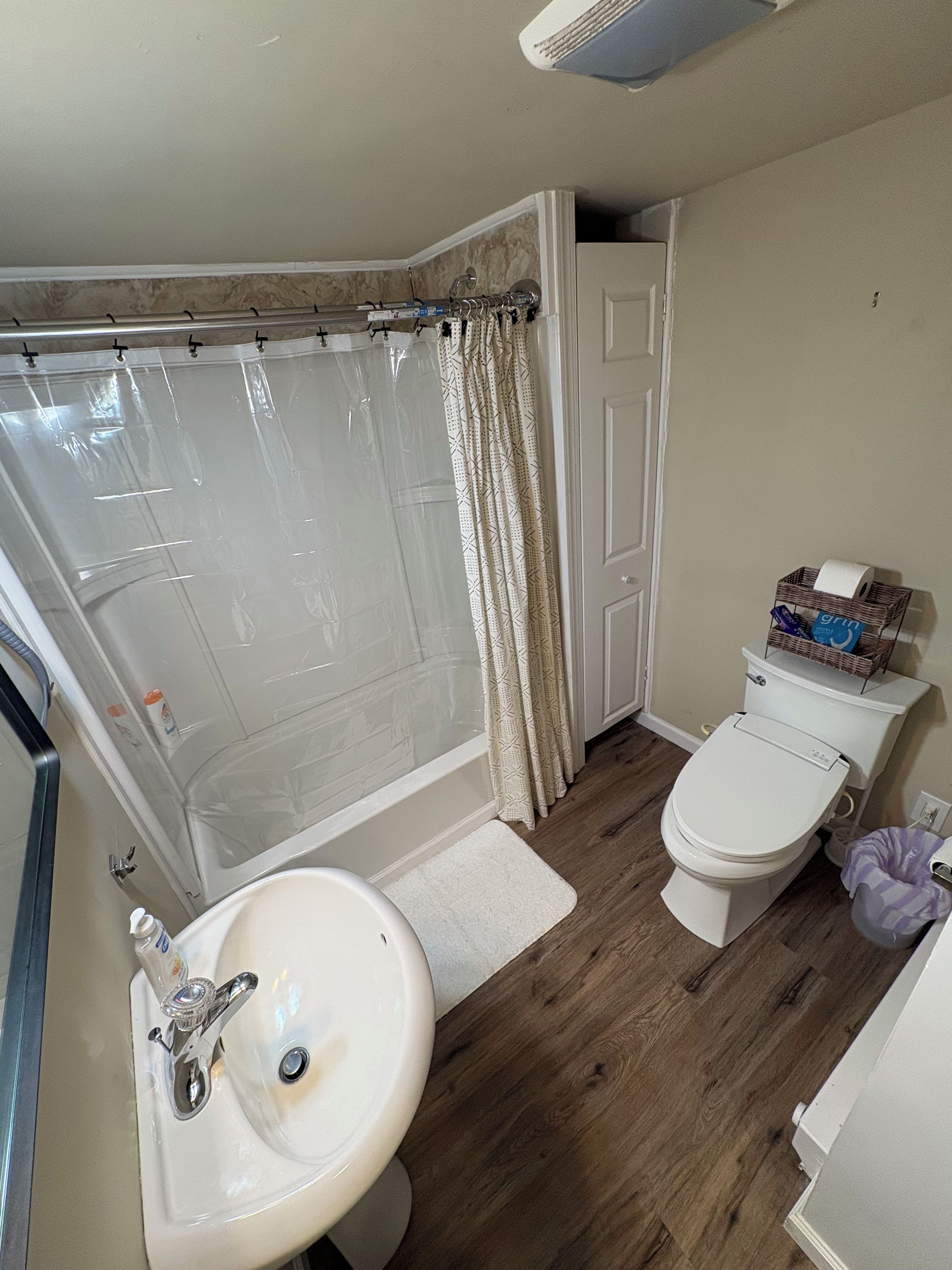 A bathroom with a shower, toilet, sink, and a towel rack.