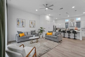 Ein modernes Wohnzimmer mit zwei Sofas, einem Couchtisch und einem Essbereich mit Barhocker.