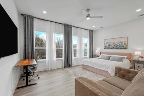 Ein modernes Schlafzimmer mit Bett, Schreibtisch, Stuhl und Sofa.