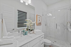 Ein modernes Badezimmer mit einem großen Spiegel, einer Dusche mit Glastür und einer Toilette.