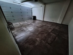 Quarto com porta de rolo cinza fechada, piso de azulejo e parede branca.
