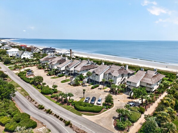 Un quartier résidentiel situé sur la côte, avec des propriétés donnant sur la plage, une route principale et un parking.