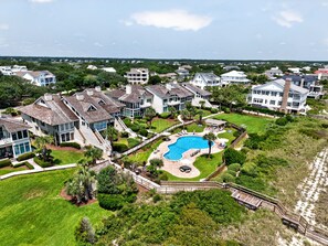 A residential area with multiple houses, a large swimming pool, and a wooden deck. - Oceanfront 3 Bedroom Villa with Community Pool (Georgetown)