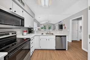 A modern kitchen with white cabinetry, a stainless steel dishwasher, and a microwave. - Palmetto Paradise, Pet Dogs ONLY 20lbs max Pool, Golf & Fairway Views (Pawleys Island)