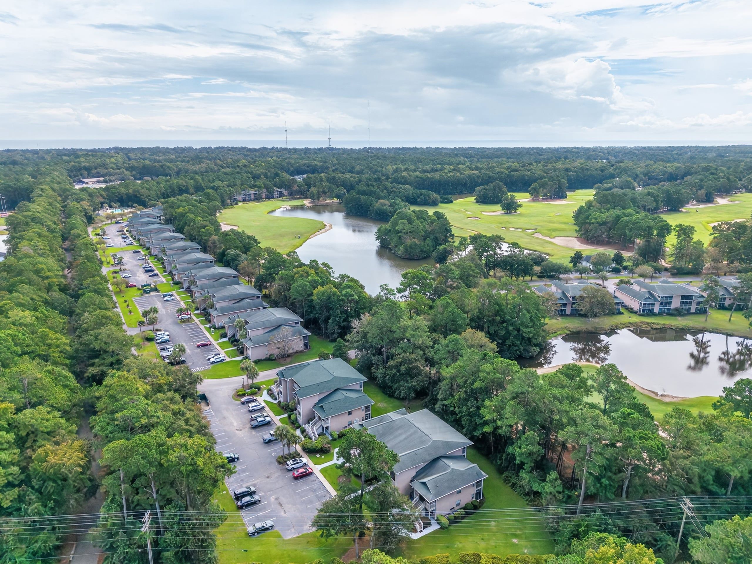 A golf course with a parking lot and buildings.