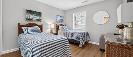 A bedroom with two beds, a round mirror, and artwork on the walls.