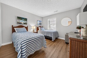 A bedroom with two beds, a round mirror, and artwork on the walls. - Palmetto Paradise, Pet Dogs ONLY 20lbs max Pool, Golf & Fairway Views (Pawleys Island)