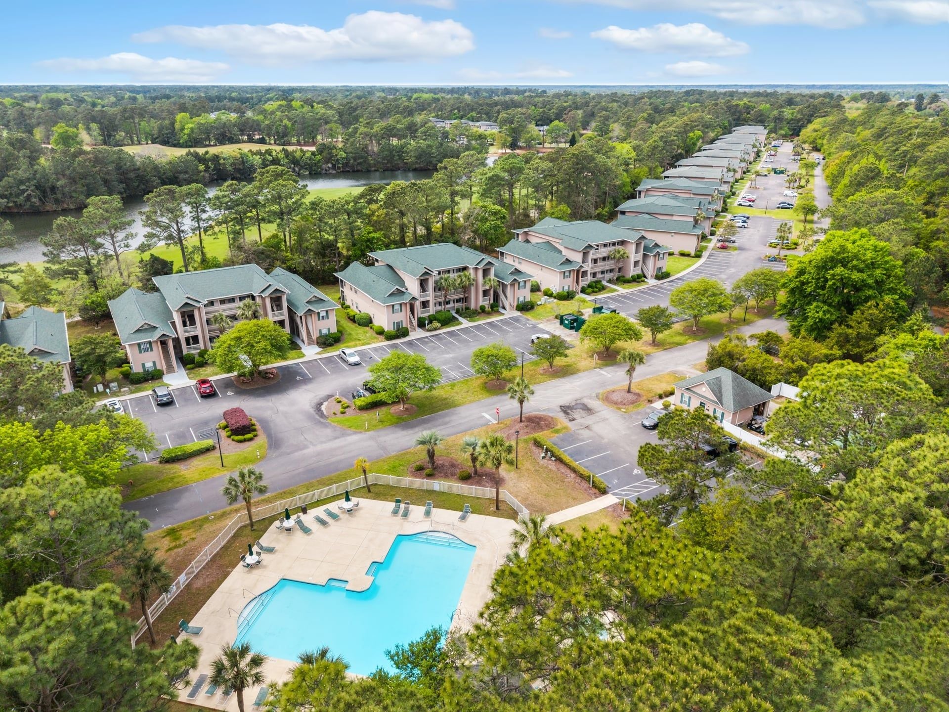 A resort with multiple buildings, a swimming pool, and a parking lot.
