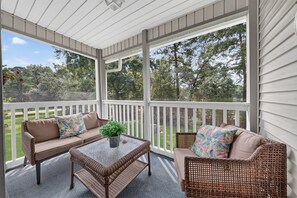 A covered porch with wicker furniture, a glass coffee table, and a potted plant. - Palmetto Paradise, Pet Dogs ONLY 20lbs max Pool, Golf & Fairway Views (Pawleys Island)